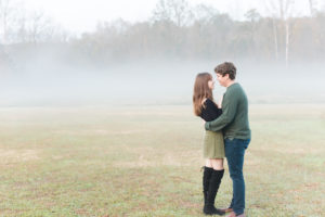 Couple gaze at each other in field of fog