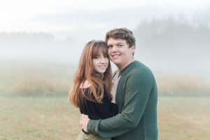 Couple smiles as fog rolls up behind them