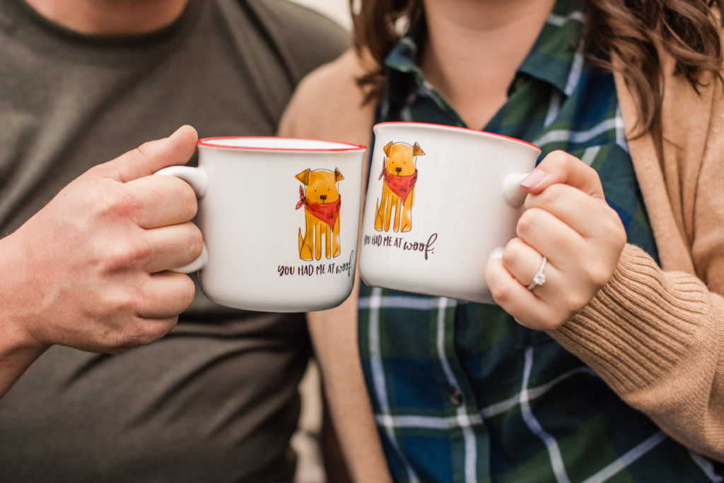 Close up of a couple toasting with dog coffee mugs at their camping themed engagement session