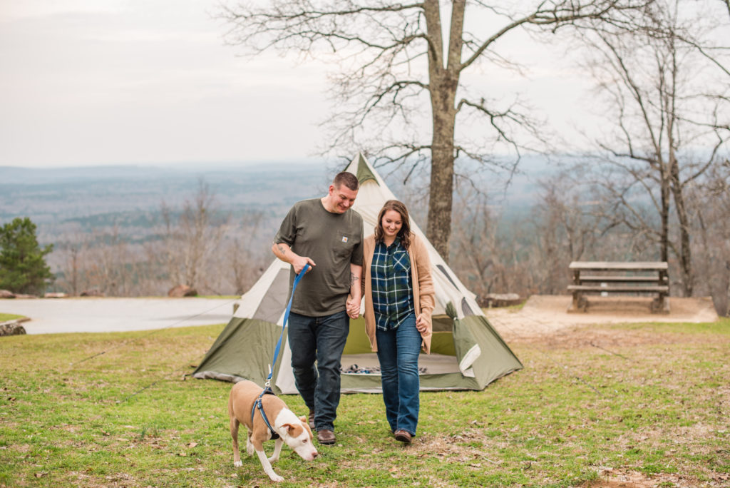 Couple wearing green walking gather dog in front of tent at their engagement session at FD Roosevelt State Park