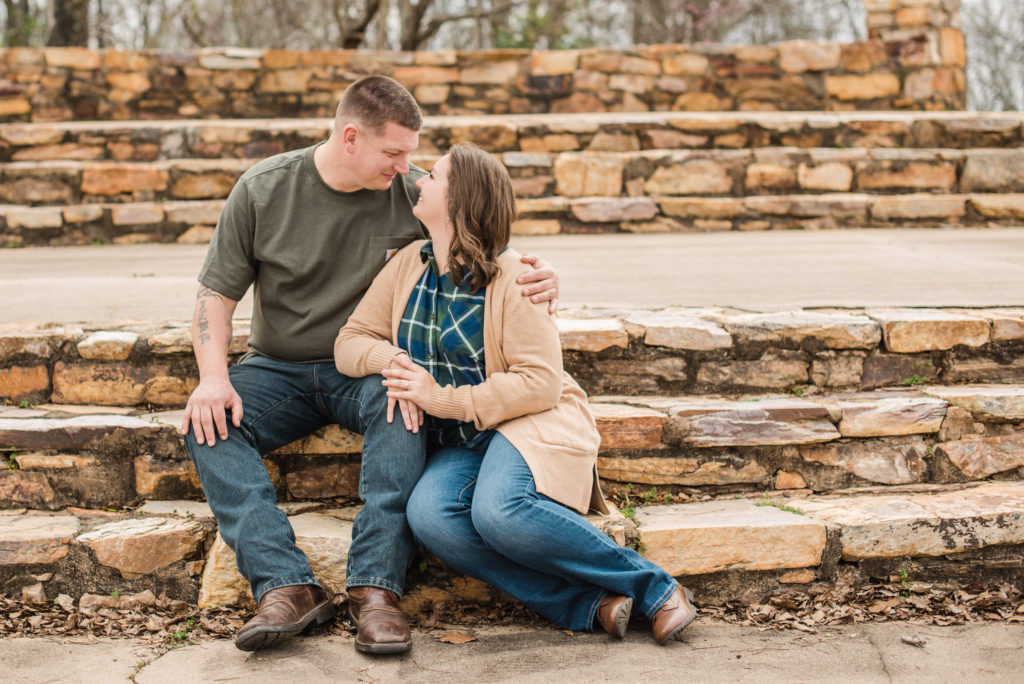 Couple wearing green kissing on rock steps at their engagement session on mountain top at FD Roosevelt State park