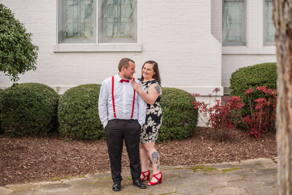 Engaged couple standing in front of bushes in Newnan GA