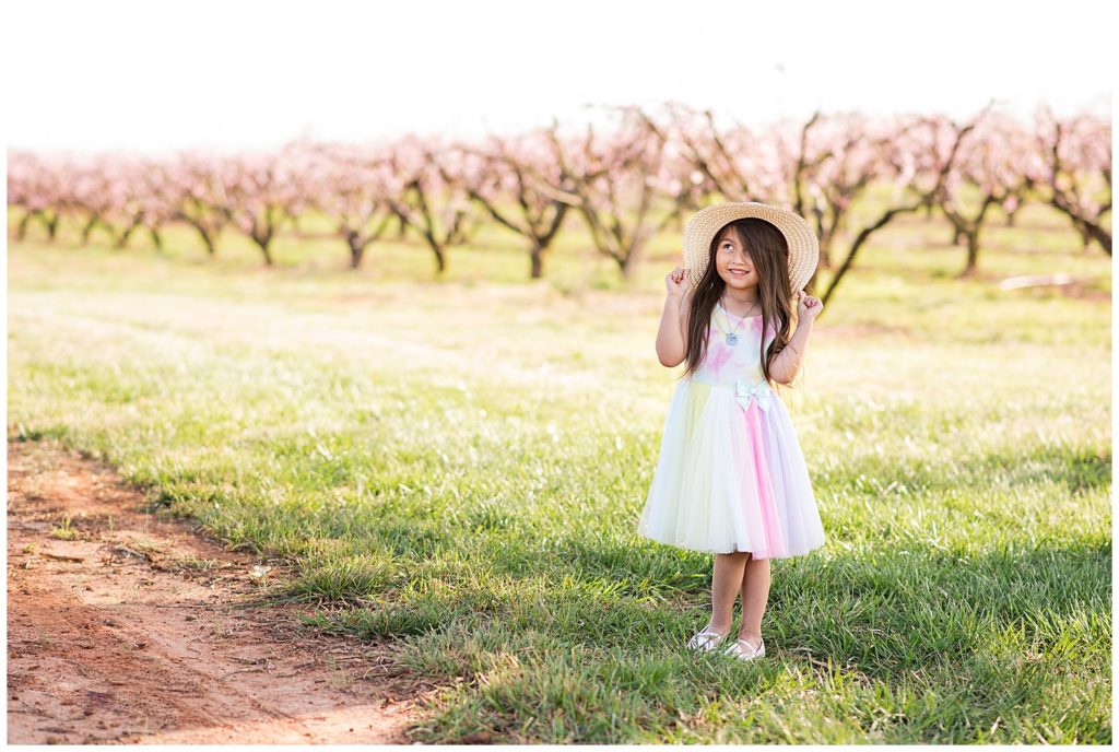 Little girl 6 years old, birthday, rainbow dress and hat, peach blossoms,